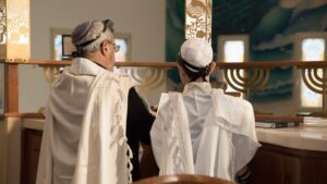 Bar mitzvah boy standing in a synagogue reading from torah.