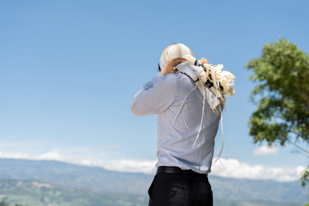 Man warpping four cornered garment, tzitzit around his head