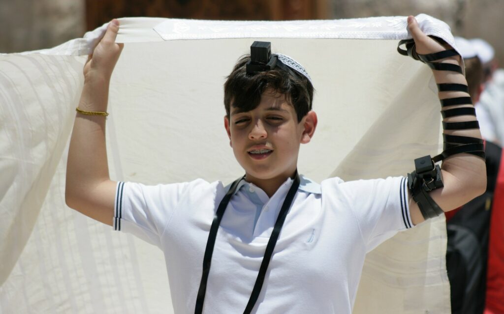 Bar mitzvah boy putting on tallit and tefillin.