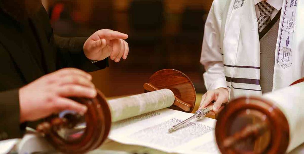 Bar mitzvah boy standing in front of the torah about to read.